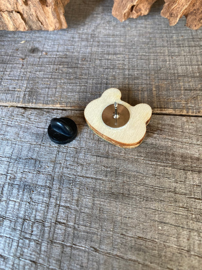 Reverse of the frog cork pin badge on weathered wood showing FSC-certified ply base, metal pin stem and black rubber clasp — secured and finished for everyday wear