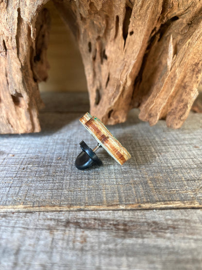 Side profile of the frog cork pin badge propped against driftwood showing cork top layer, FSC ply base and black rubber pin clasp — eco-friendly handmade badge