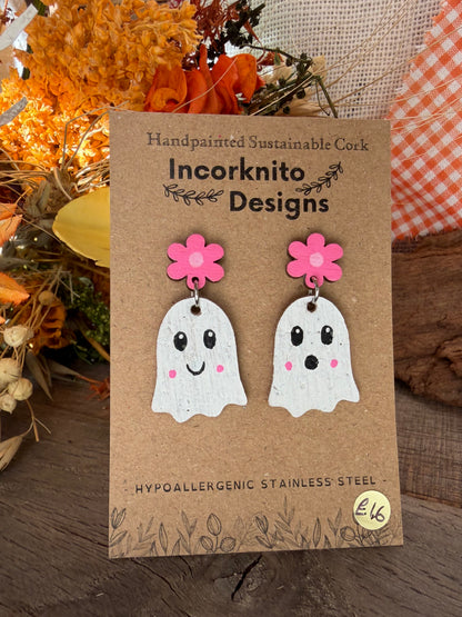 Close-up of white cork ghost drops with pink flower tops, black eyes and rosy cheeks on a branded display card.