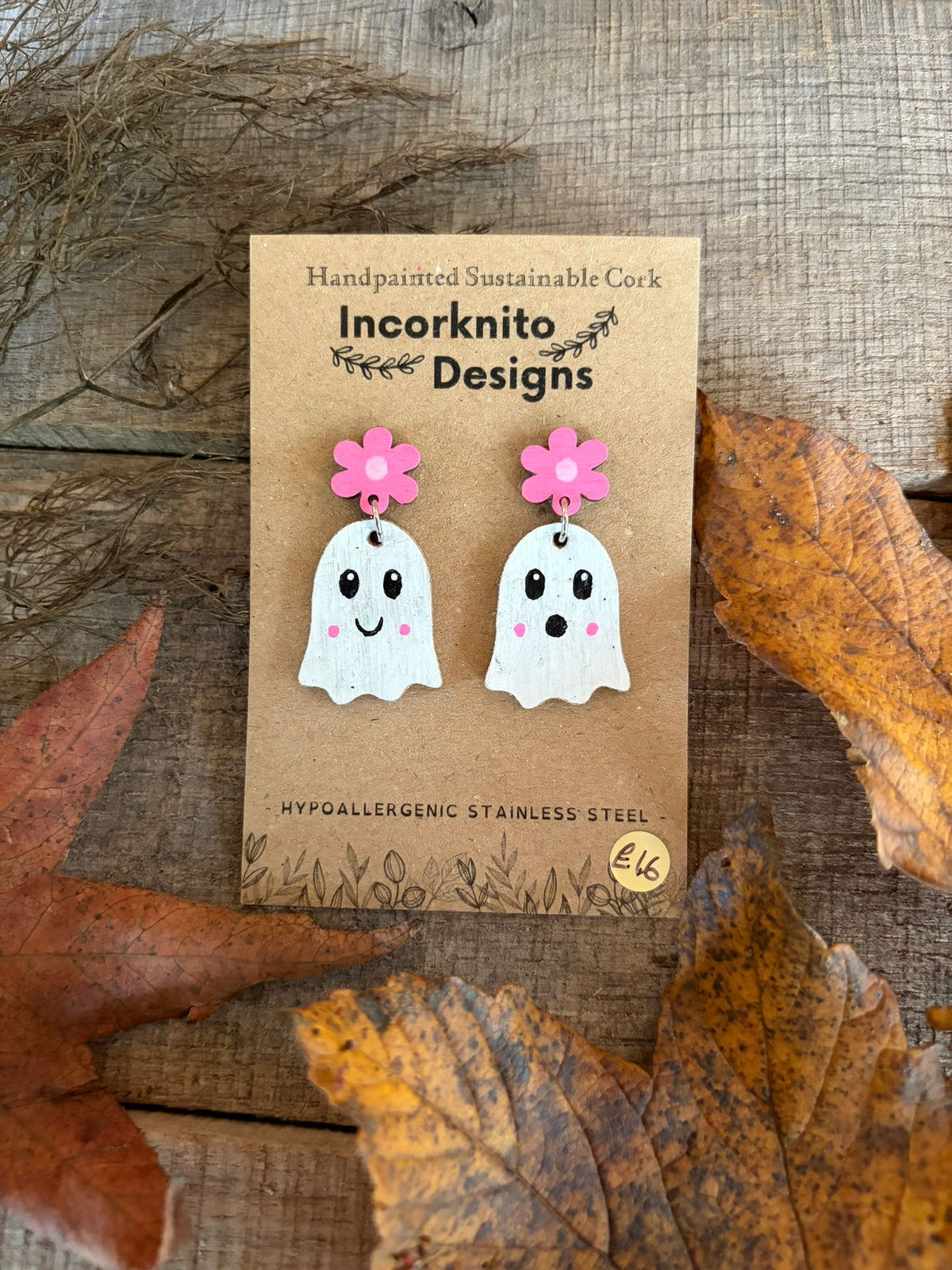 Pink flower stud-top ghost earrings on a kraft display card surrounded by autumn leaves.