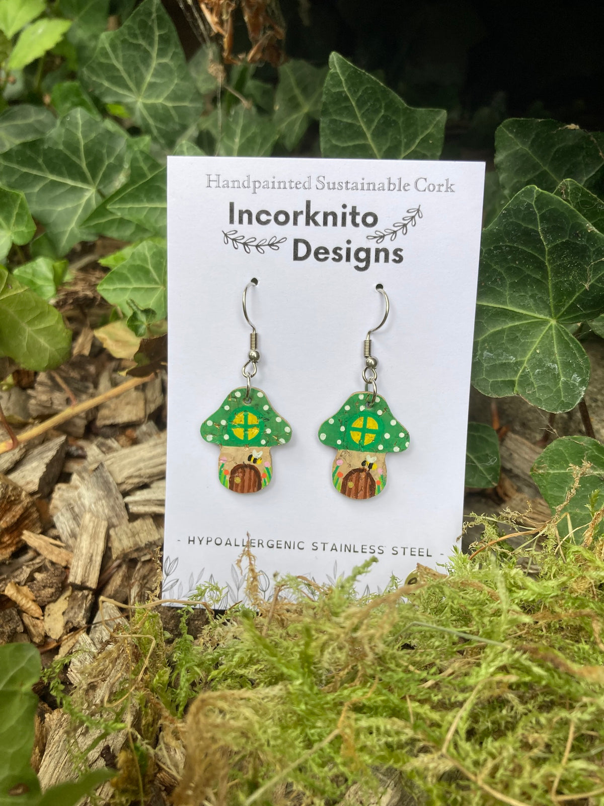 Green Fairy House Toadstool Earrings on an Incorknito Designs card with green ivy background