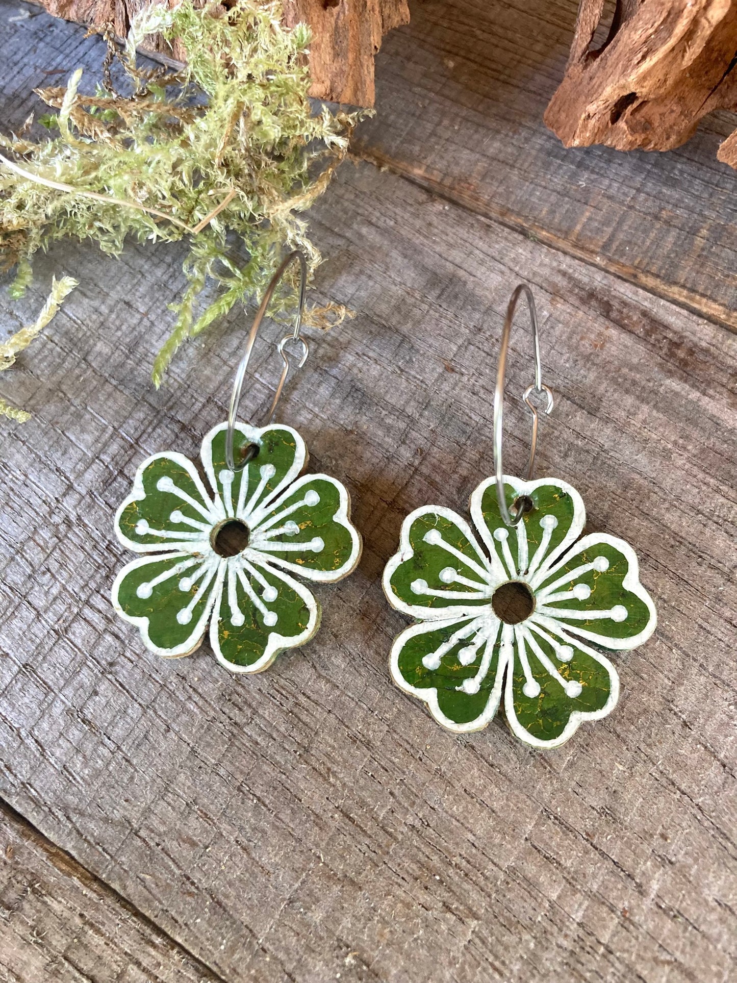 Green large flower cork hoop earrings flat lay on weathered wood with dried moss and driftwood — silver hoops with handpainted white pollen detail