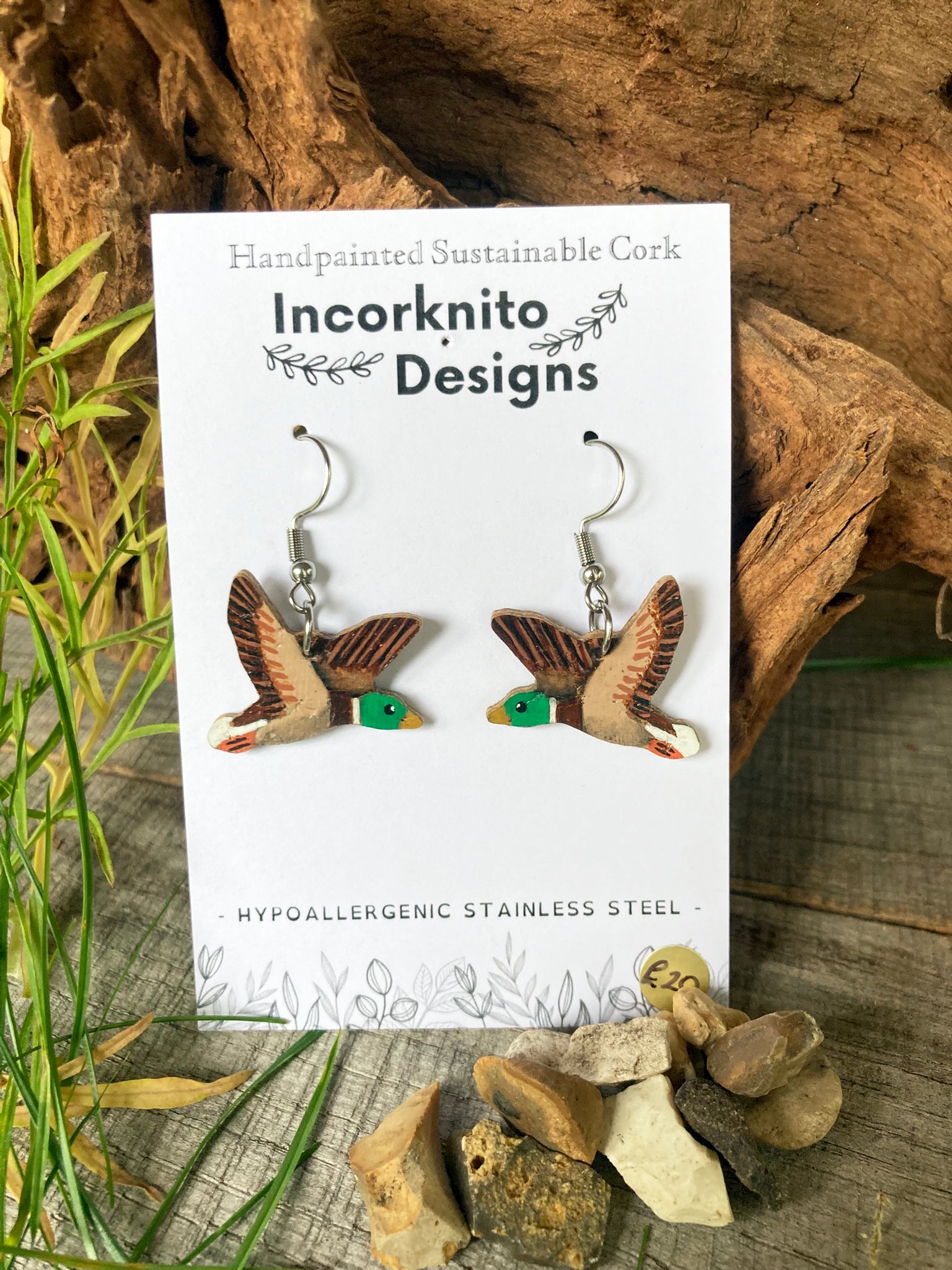 Incorknito Designs mallard drake cork earrings on natural background with green reeds and pebbles
