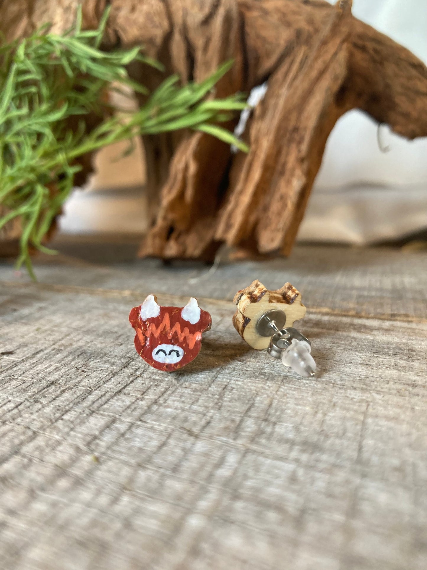 Front and reverse view of highland cow cork stud earrings — painted face on front, plain FSC wood back with butterfly and silicone backs shown