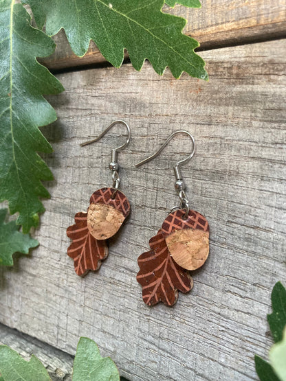 Cork acorn and oak leaf earrings in green colourway flat lay on weathered wood surrounded by real oak leaves