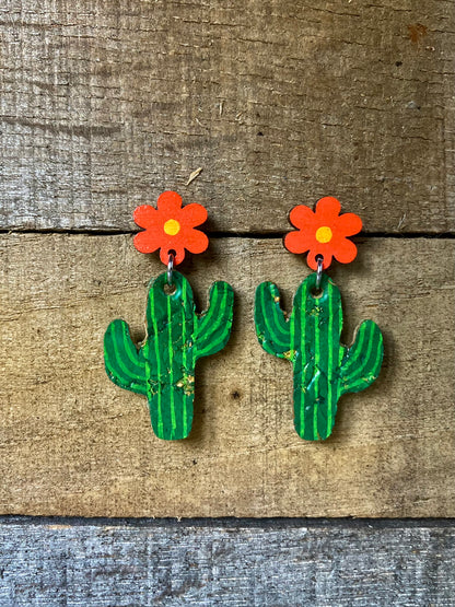 Cacti flower stud drop earrings in orange, handpainted cork cactus with orange wooden flower stud top, flat lay on weathered wood