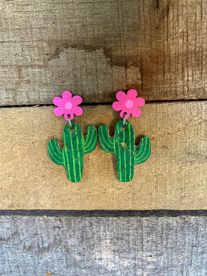Cacti flower stud drop earrings in pink, handpainted cork cactus with pink wooden flower stud top, flat lay on weathered wood