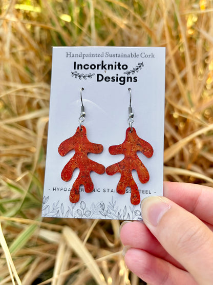 Orange handpainted cork coral earrings on an Incorknito Designs card, held against a golden straw background