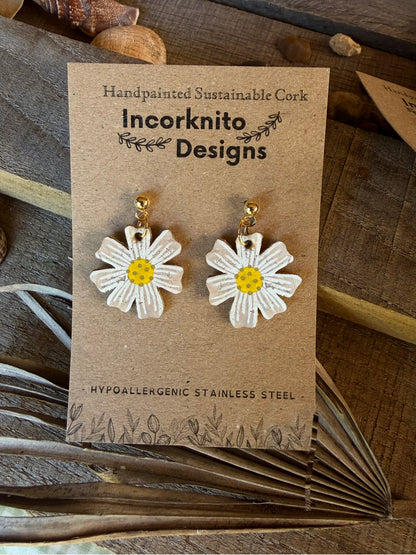 Handpainted cork daisy earrings on gold ball studs, displayed on Incorknito Designs branded card with dried palm leaf and wooden background