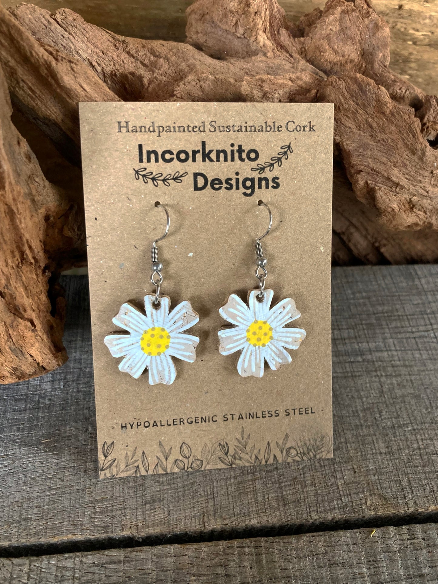Handpainted cork daisy earrings on silver hooks, displayed on Incorknito Designs branded card with cork bark background