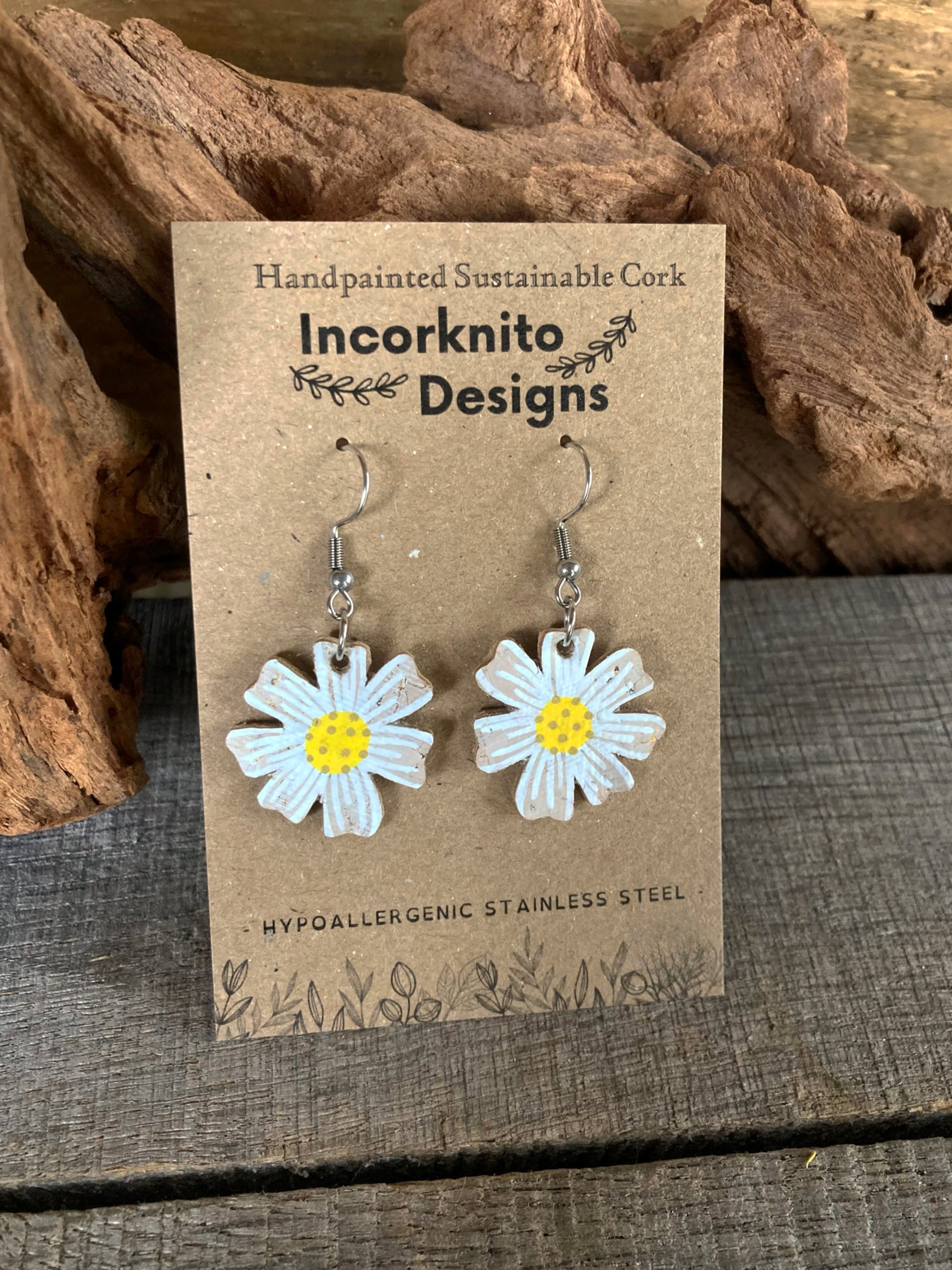 Handpainted cork daisy earrings on silver hooks, displayed on Incorknito Designs branded card with cork bark background