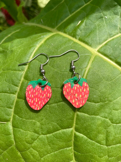 Cork large strawberry earrings on silver hooks, flat lay on a large green leaf