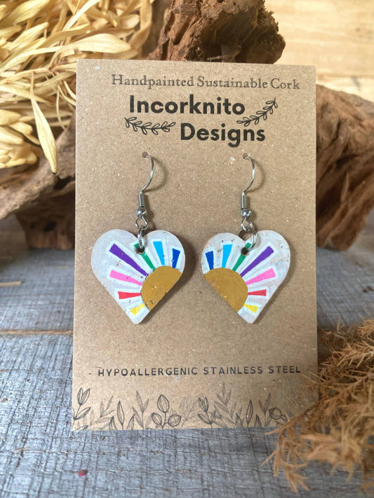 Handpainted rainbow sun heart cork earrings on silver hooks, displayed on Incorknito Designs branded card with cork bark and dried grass background