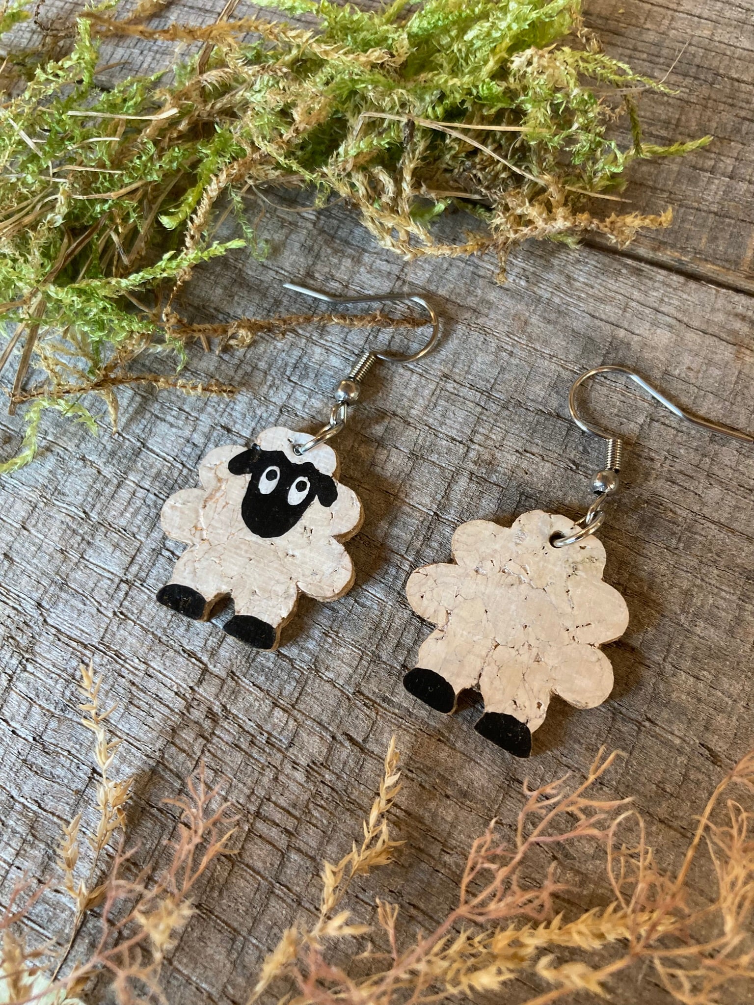 Cork sheep earrings showing front and reverse — handpainted white sheep face on front, natural cork texture on reverse painted white, with black feet on both sides