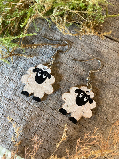 Cork sheep earrings on silver hooks, flat lay on weathered wood with dried green moss and grass