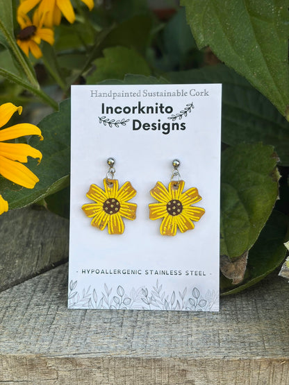 Handpainted cork sunflower earrings on silver ball studs, displayed on Incorknito Designs branded card surrounded by rudbekia