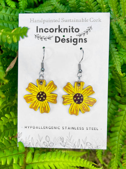 Handpainted cork sunflower earrings on silver hooks, displayed on Incorknito Designs branded card with fern background