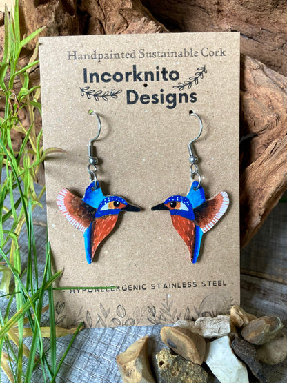 Kingfisher cork earrings on Incorknito Designs card with driftwood and pebbles — handpainted sustainable bird jewellery