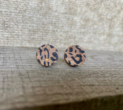 Handpainted leopard print cork stud earrings with black spots and gold fleck with a linen surface background