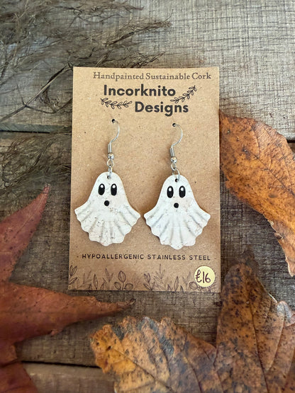 White cork ghost drops with black oval eyes and little open mouths, displayed on hooks among autumn leaves.