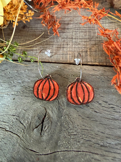 Lightweight orange pumpkin cork earrings with silver open back hoops and clear rubber backs, styled on rustic wood beneath autumn foliage.