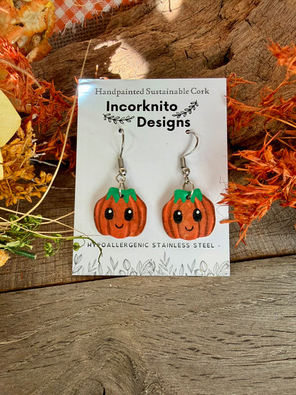 Handmade Mini Smiley Pumpkin earrings with silver hooks on a white Incorknito Designs card, framed by dried orange and yellow foliage.