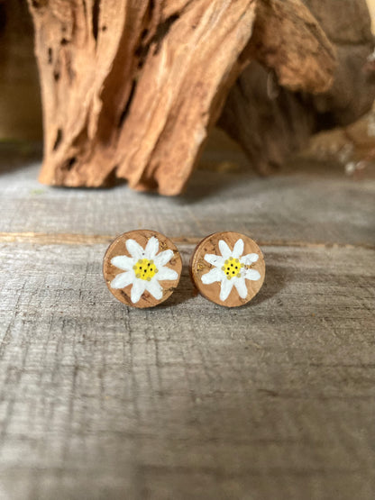 Natural cork daisy stud earrings with white daisy on uncoloured cork background on a wooden surface