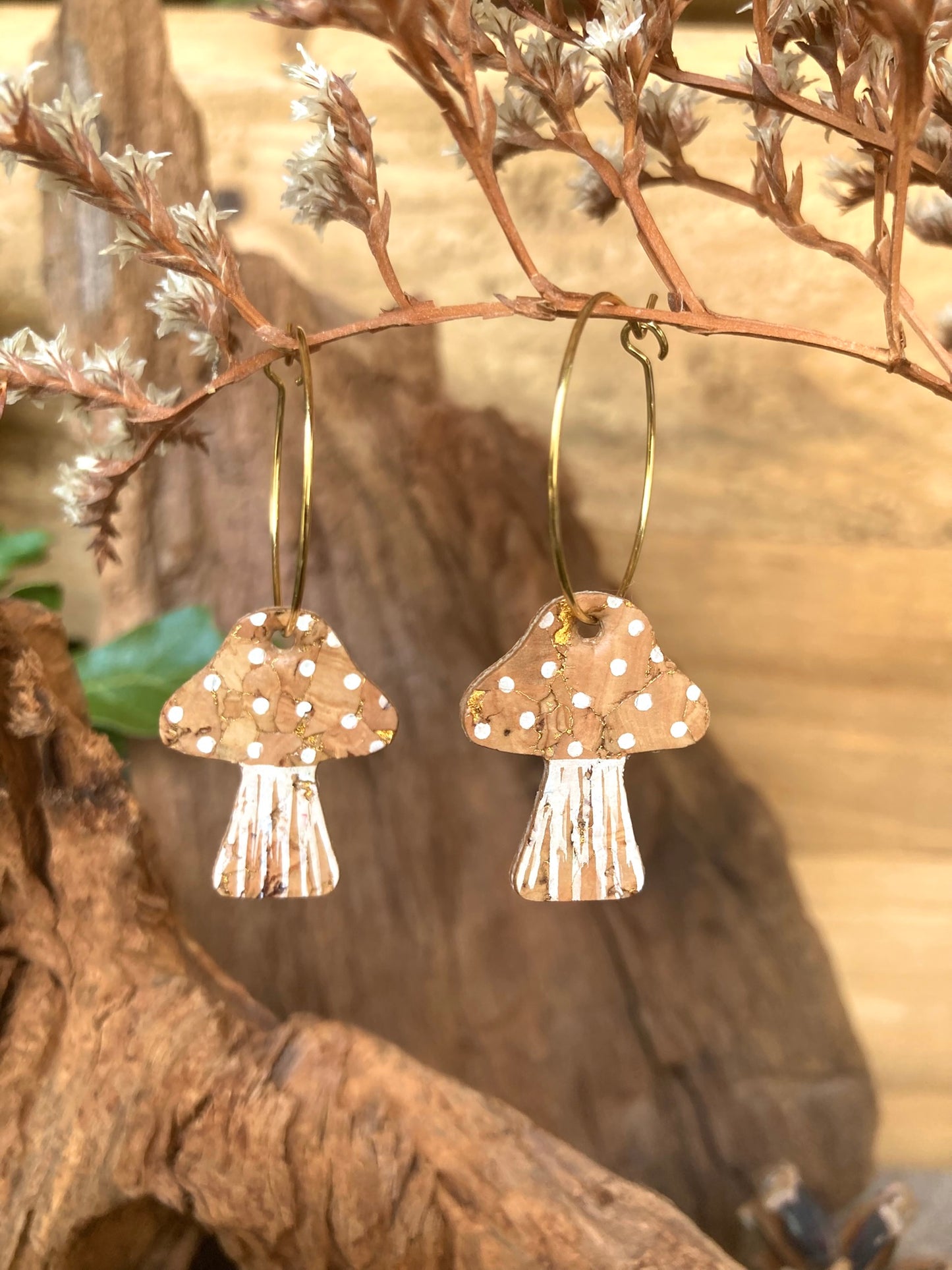 Natural toadstool cork large hoop earrings hanging from a dried branch — gold hoops with natural cork cap and white polka dots
