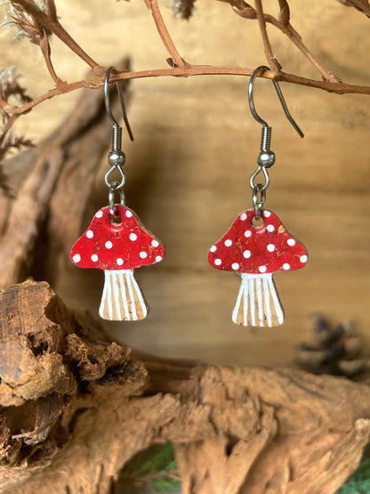 Red toadstool cork medium earrings hanging from a dried branch — silver hook fastening with handpainted white spot detail