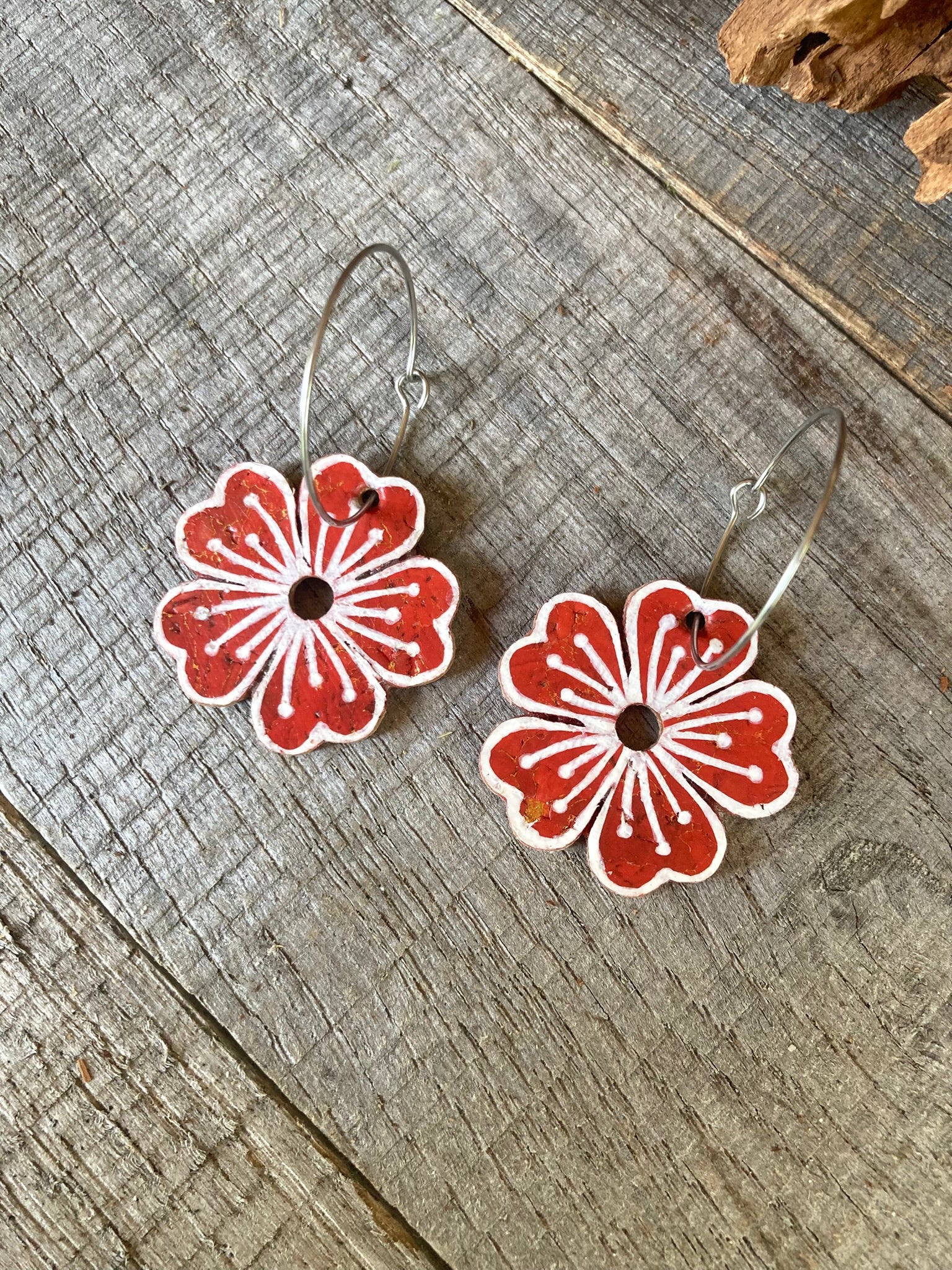 Rust large flower cork hoop earrings flat lay on weathered wood — silver hoops with handpainted white pollen detail and gold fleck cork
