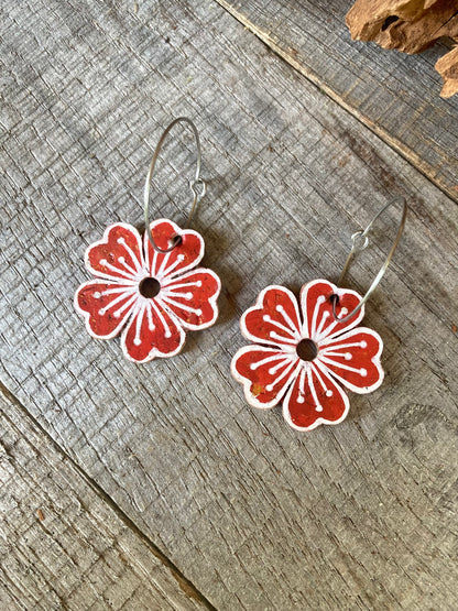 Rust large flower cork hoop earrings flat lay on weathered wood — silver hoops with handpainted white pollen detail and gold fleck cork
