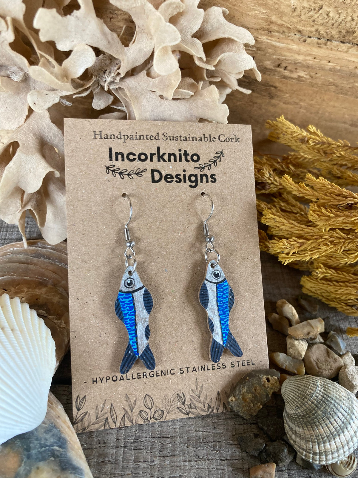 Sardine cork earrings on silver hooks on Incorknito Designs branded card with shells and coastal foliage