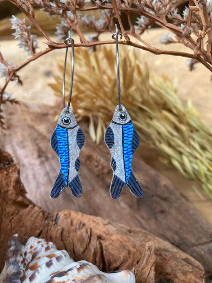 Handpainted fish cork hoop earrings hanging from a dried branch — eco-friendly jewellery handmade in Suffolk