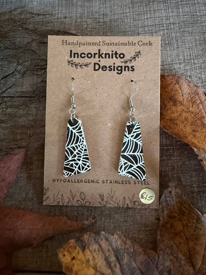 SW6 wide tapered spider-web cork earrings on silver hooks, with an intricate arrangement of white webs across the black painted surface.